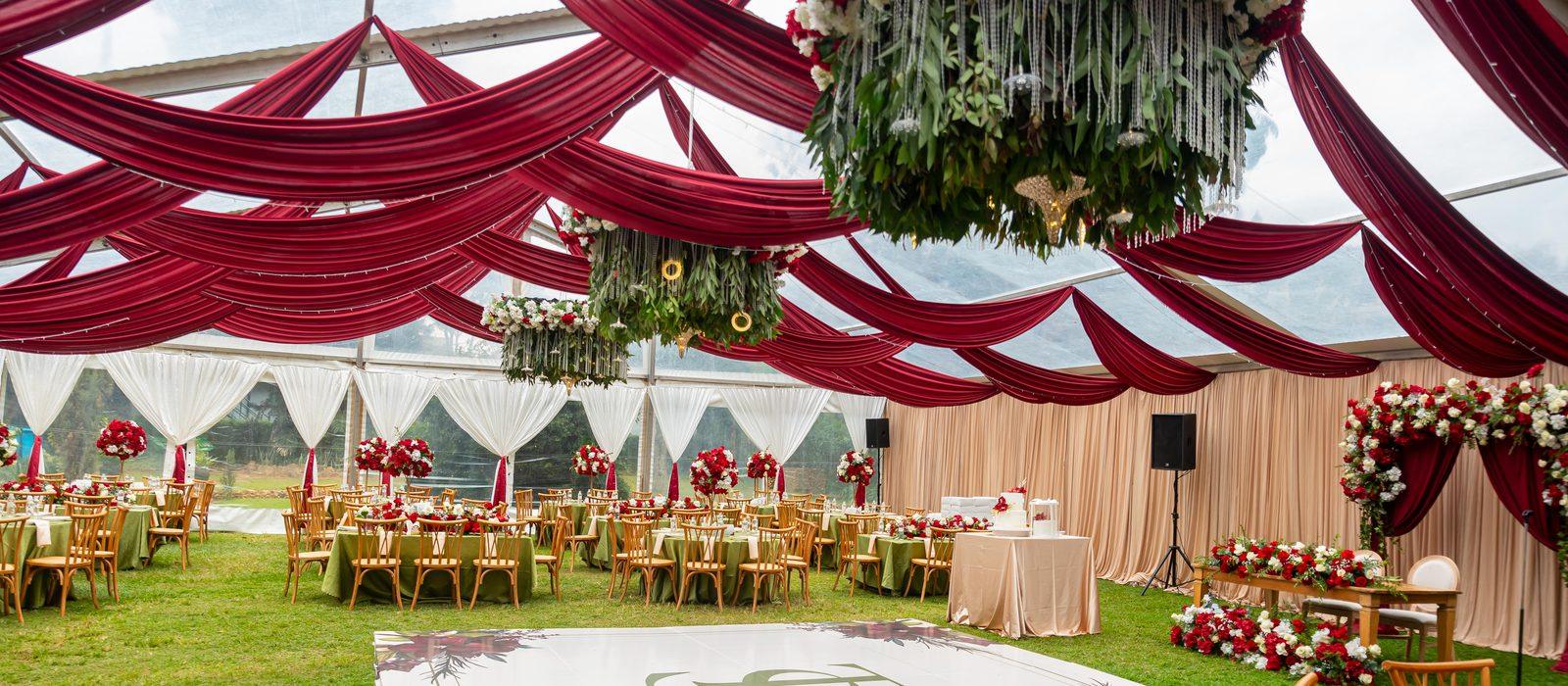 Red and ivory draping, hanging floral chandeliers and rose centrepieces in a marquee, styled by Pearls and Roses