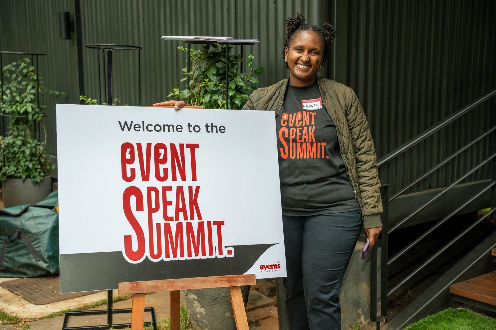 A crew member beside the Event Speak Summit welcome sign